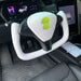 Car interior with a white steering wheel cover featuring green leaf designs.